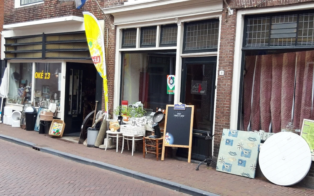 Gevel van kringloopwinkel met etalage, stoelen en spullen op het terras