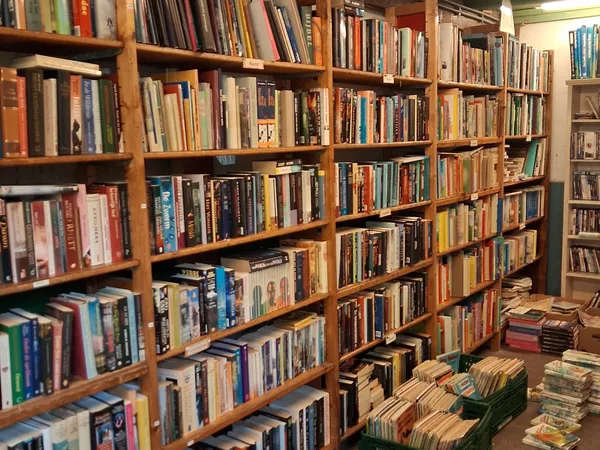 Houten stellingen vol met dvd's, blu-rays en cd's in een tweedehandswinkel