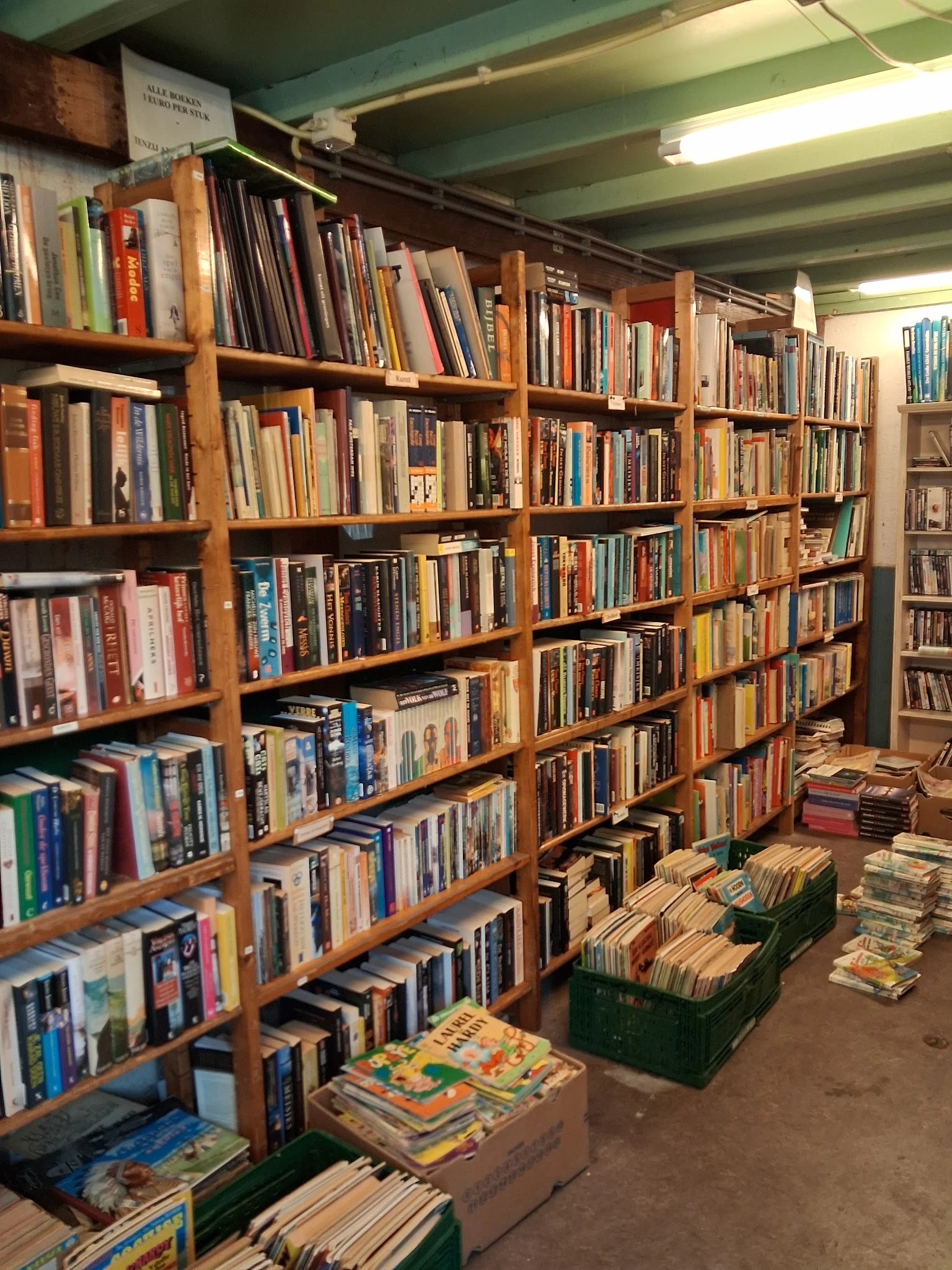 Houten stellingen vol met dvd's, blu-rays en cd's in een tweedehandswinkel