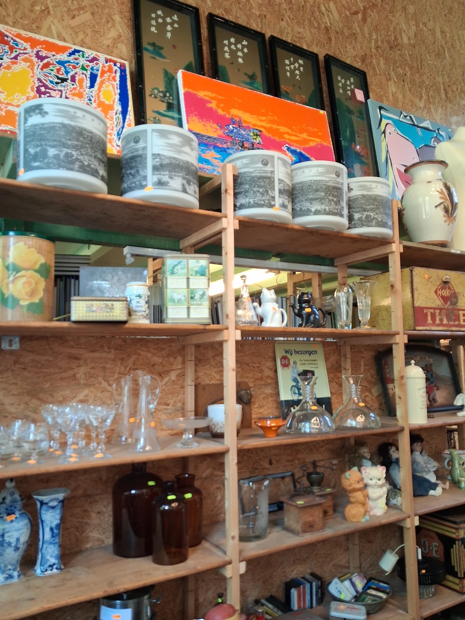Houten stellingen met diverse tweedehands huishoudartikelen, glazen potten en decoratiespullen