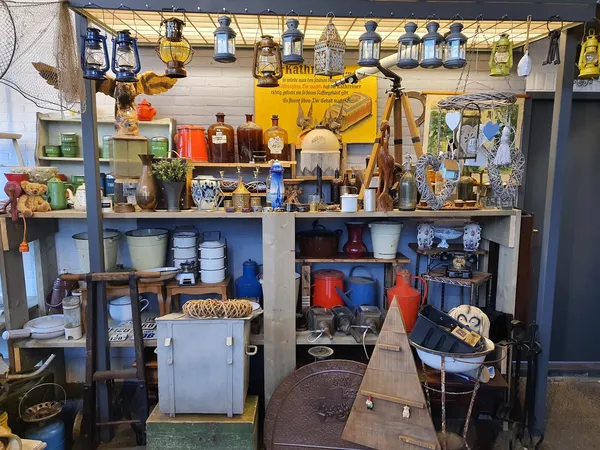 Winkelinterieur met stellingen vol antieke objecten, lampen, servies, boeken en decorstukken