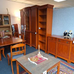 Showroom met houten meubels: eettafel met stoelen, kasten en dressoirs op blauwe vloer met tapijten