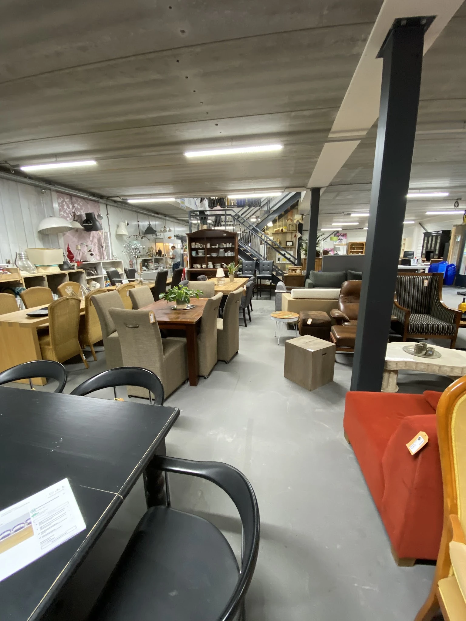 Ruim winkelinterieur met diverse meubels, zithoeken en stellingen met decoratieve voorwerpen