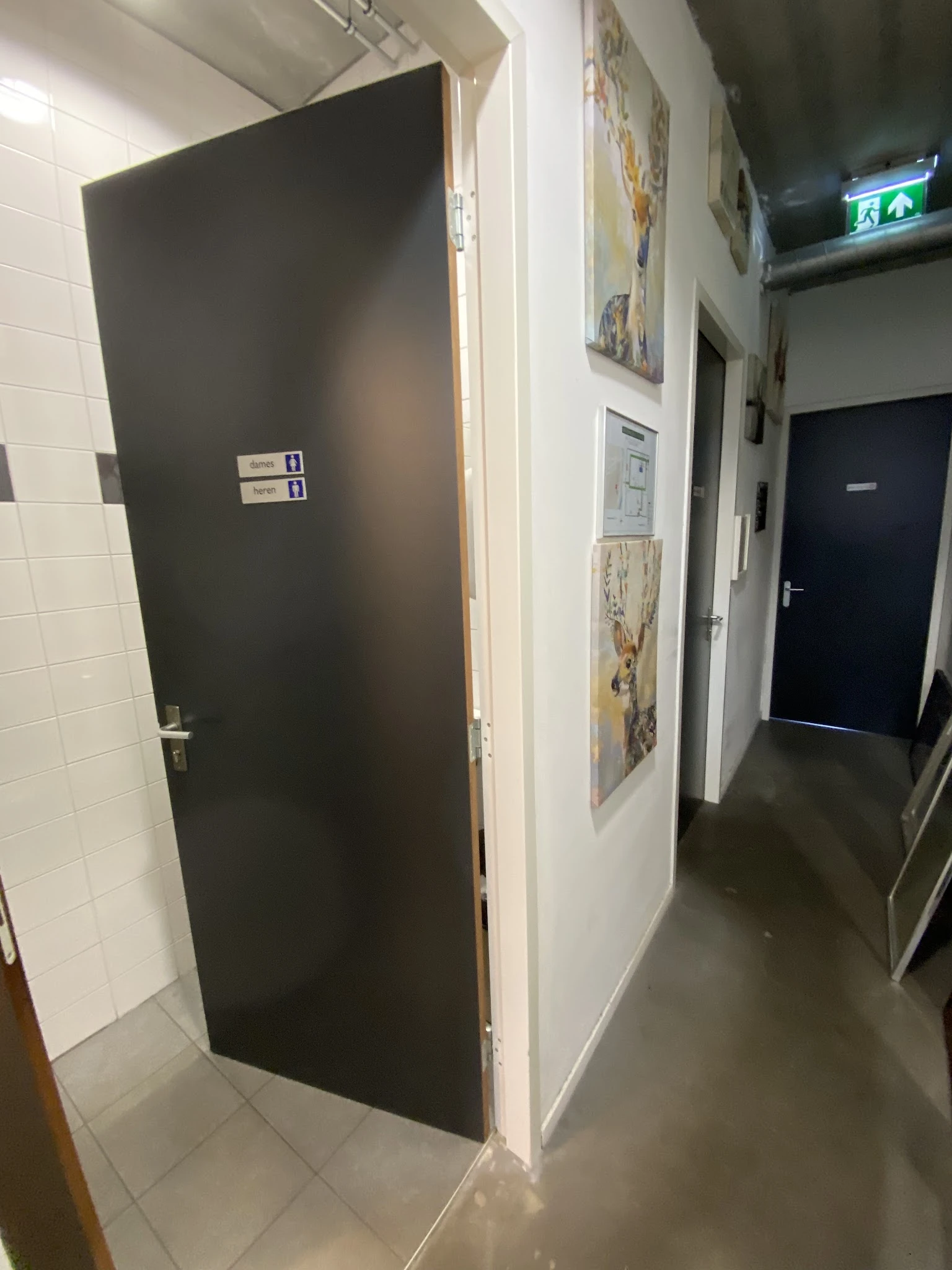 Hal met deuren, stellingen en diverse affiches aan de wand