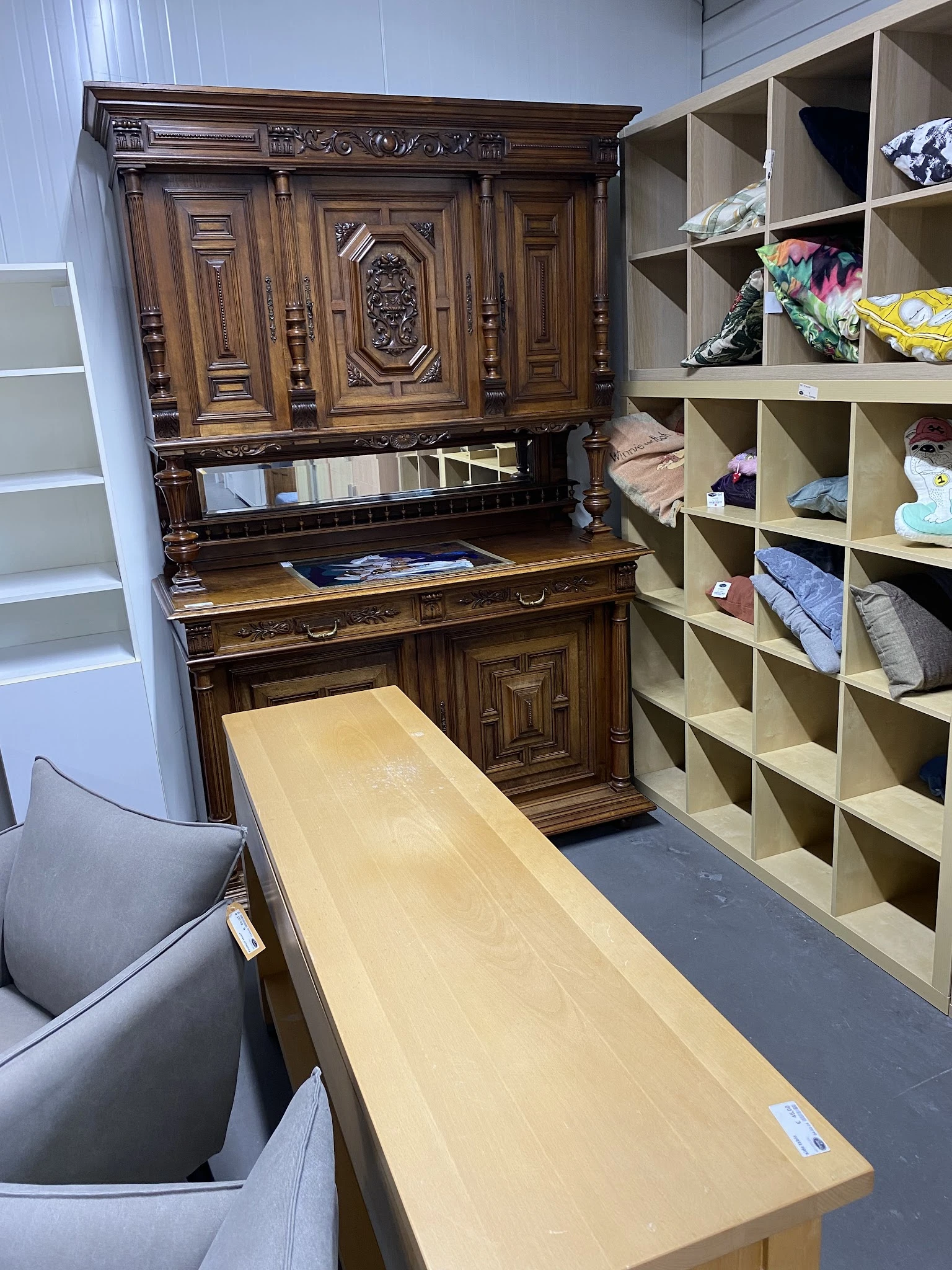 Winkelinterieur met houten bureau, boekenrek en witte stellingen met textiel en huishoudartikelen