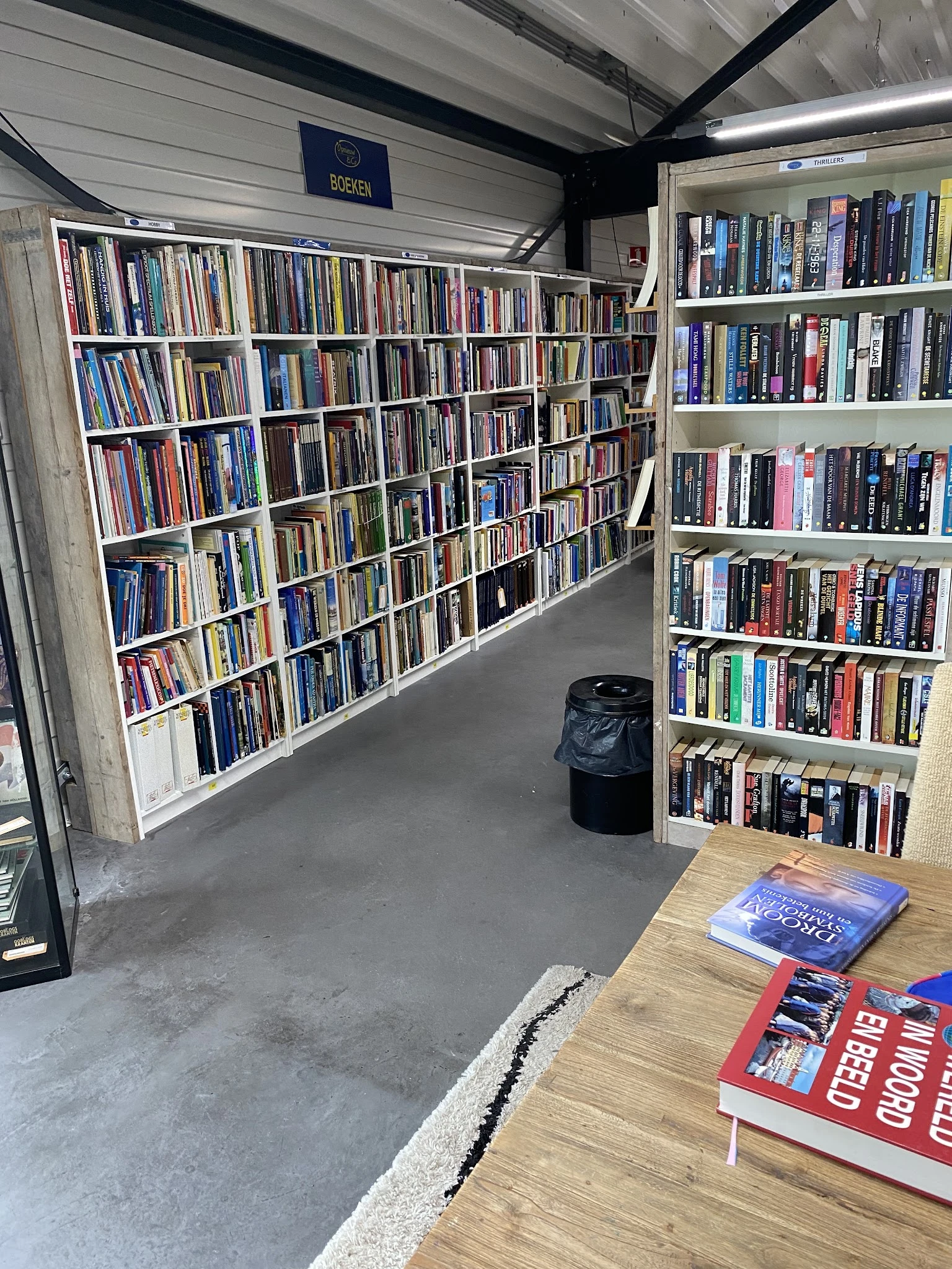 Binnenaanzicht van kringloopwinkel met uitgebreide cd- en dvd-collectie op stellingen en een tafel op de voorgrond