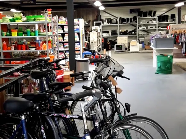 Winkelvloer met fietsen op de voorgrond en rekken met kleding en huishoudelijke spullen op de achtergrond