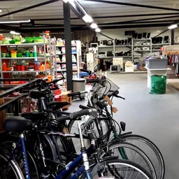Winkelvloer met fietsen op de voorgrond en rekken met kleding en huishoudelijke spullen op de achtergrond