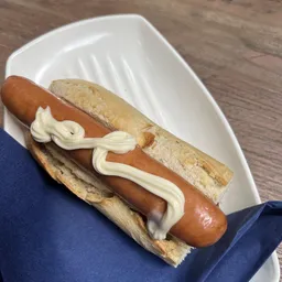 Hotdog met worst en mayonaise op een wit bordje