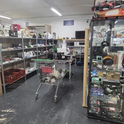 Winkelvloer met stellingen, winkelwagen en diverse artikelen in een kringloopwinkel