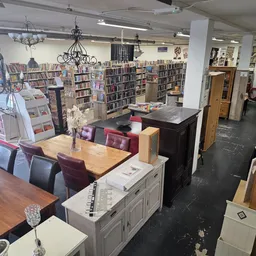 Ruim winkelbinnenruimte met boekenkasten, tafels, stoelen en diverse meubels en inrichtingsstukken