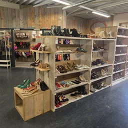 Houten stellingen met uitgestalde tweedehands schoenen, tassen en accessoires in de winkel