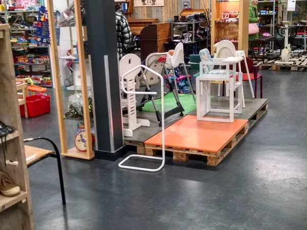 Winkelvloer met speelgoed en kinderartikelen op pallets, waaronder een schommel en kinderstoeltjes