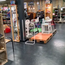 Winkelinterieur met speelgoed en meubels op oranje pallet, witte stoelen en speeltoestellen