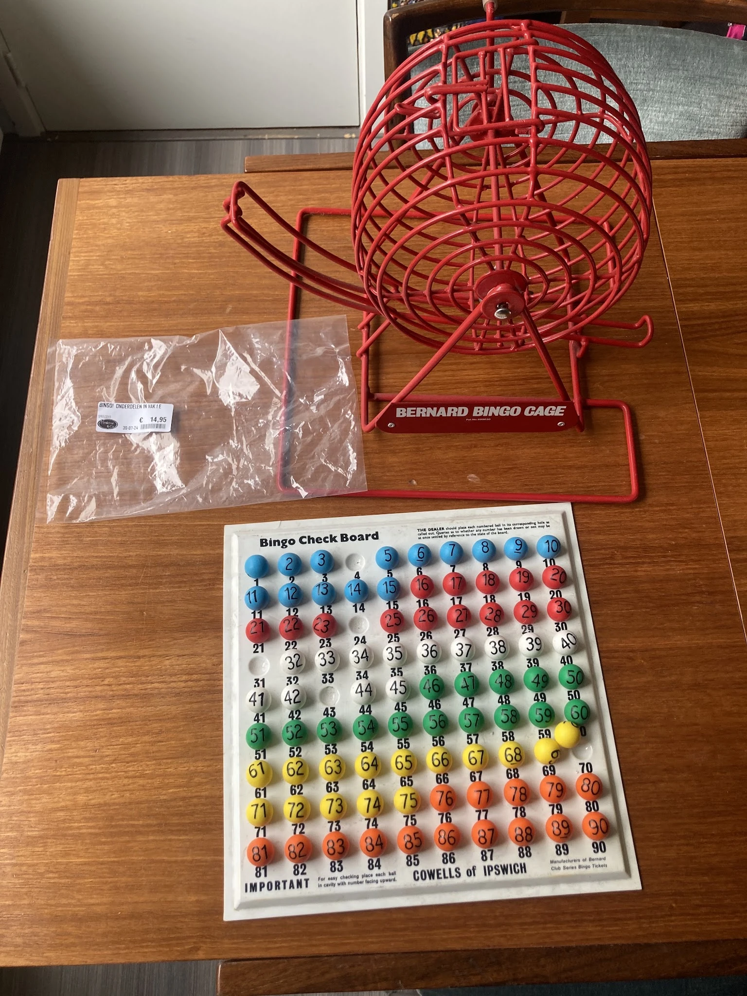 Bingo-spel met rode kooi, bingo-bordkaart en witte plastic balletjes in zakje
