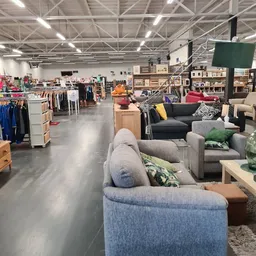 Overzicht van kringloopwinkel met meubels, kleding en huishoudspullen op de vloer