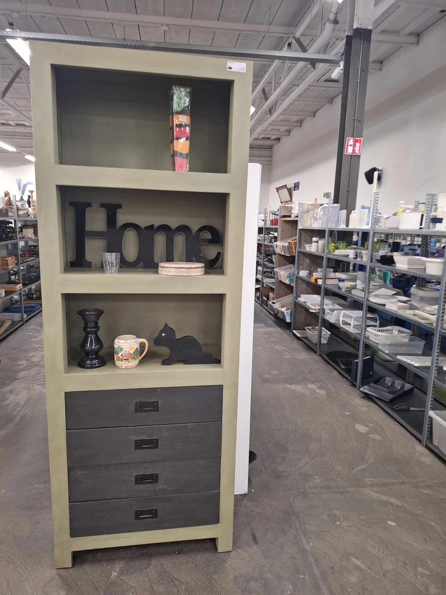 Wandrekje met 'Home' decoratie, vazen en zwarte accessoires in een kringloopwinkel