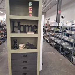 Wandrekje met 'Home' decoratie, vazen en zwarte accessoires in een kringloopwinkel