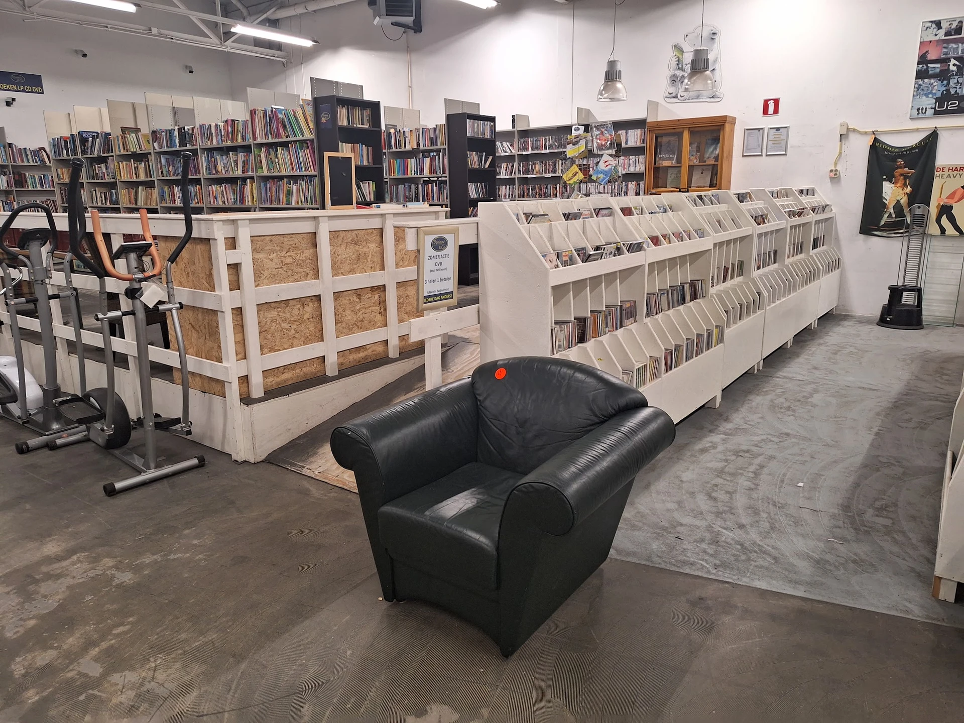 Winkelvloer met boekenrekken, stellingen en een zwarte leunstoel in het midden van de ruimte
