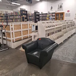 Winkelvloer met boekenrekken, stellingen en een zwarte leunstoel in het midden van de ruimte