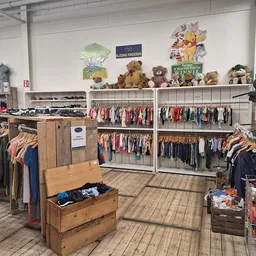 Winkelvloer met kledingrekken, houten boxen met spullen en teddyberen op bovenste planken