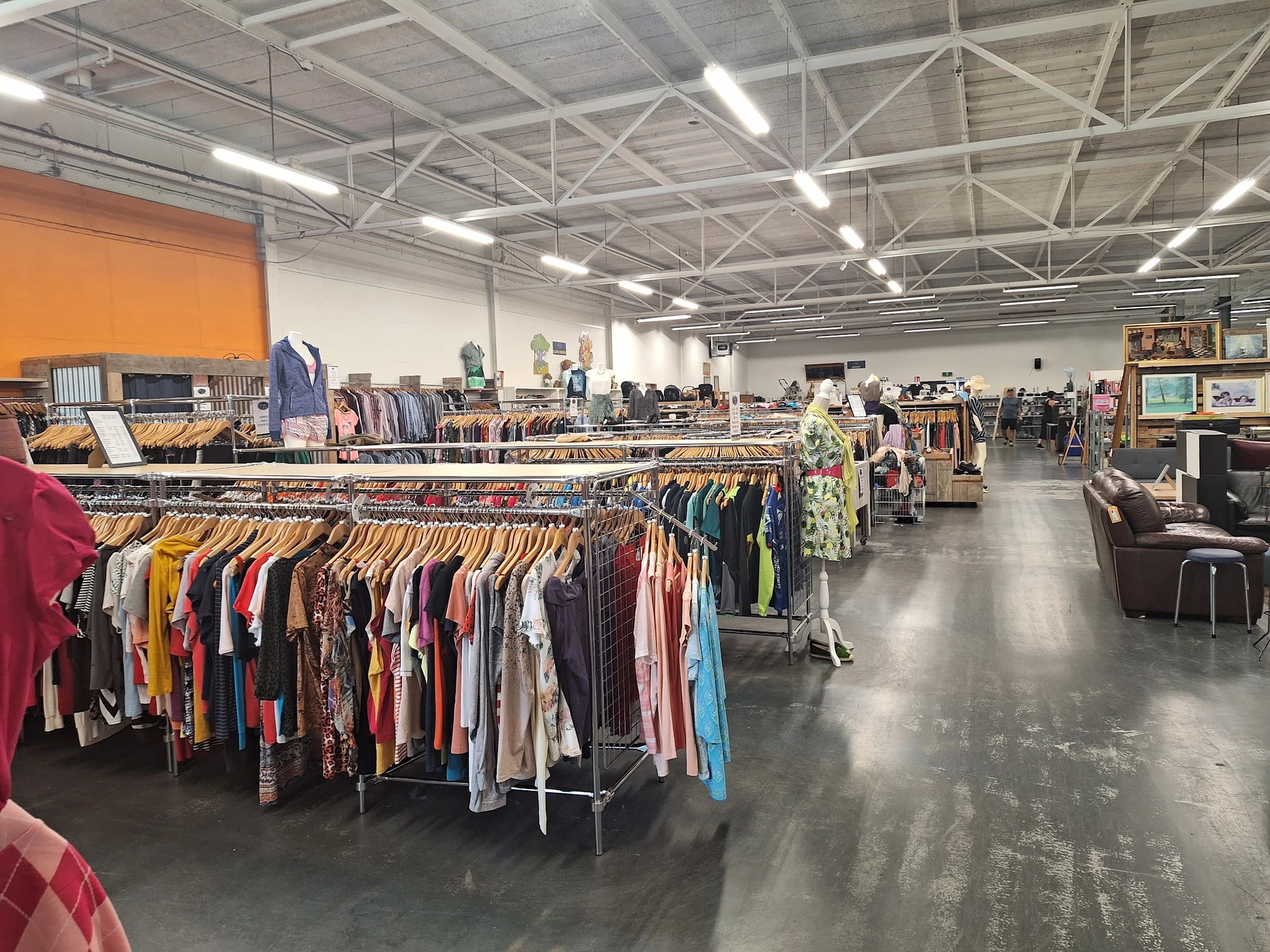 Ruim winkelinterieur met kledingrekken vol tweedehands kleding, meubels en diverse spullen
