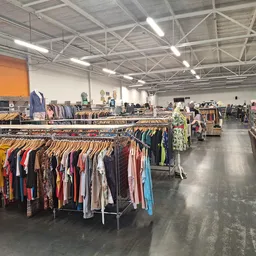 Ruim winkelinterieur met kledingrekken vol tweedehands kleding, meubels en diverse spullen