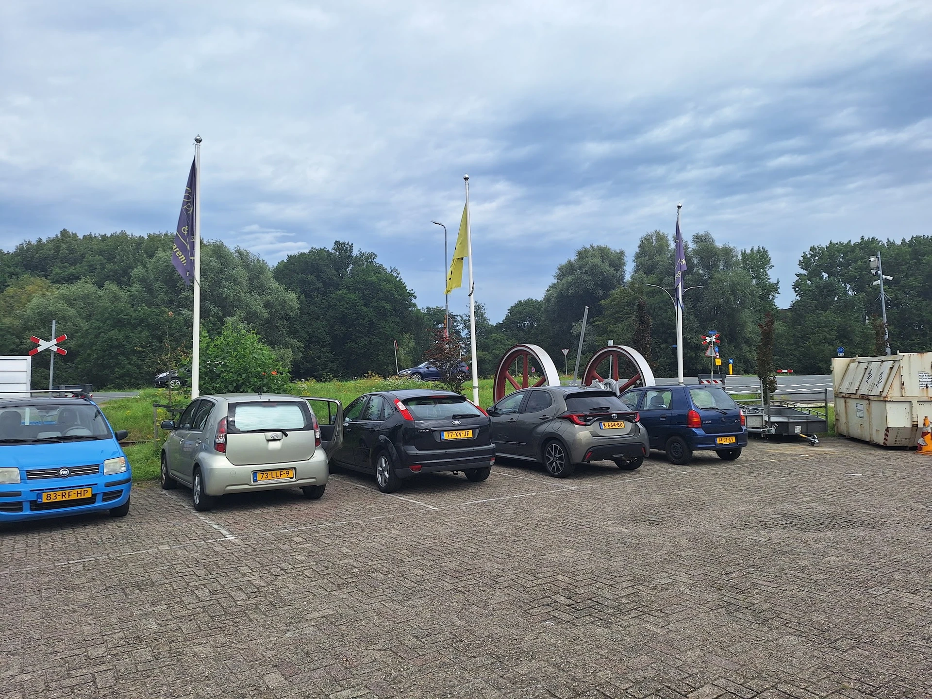 Parkeerplaats met enkele geparkeerde auto's en vlaggen in de verte