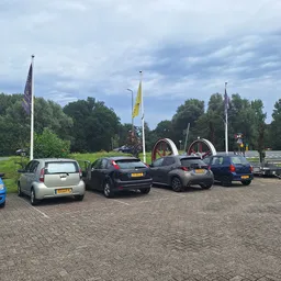 Parkeerplaats met enkele geparkeerde auto's en vlaggen in de verte