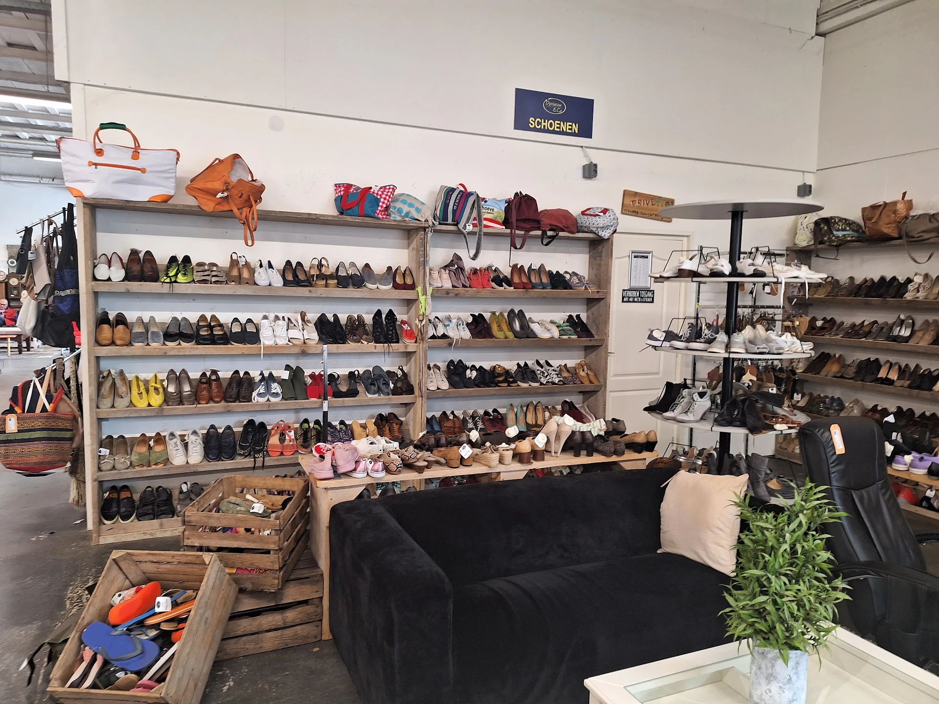 Winkelinterieur met schoenenrekken, een zwarte bank en diverse artikelen, representatief voor een kringloopwinkel