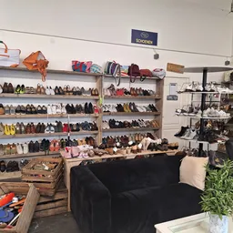 Winkelinterieur met schoenenrekken, een zwarte bank en diverse artikelen, representatief voor een kringloopwinkel
