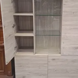 Wit houten kastje met glazen deuren en twee openstaande witte deuren met planken erbinnen