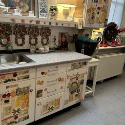 Vintage keuken met beschilderde kasten en bloempatronen, spiegelkasten en aanrechtblad in een winkelinterieur
