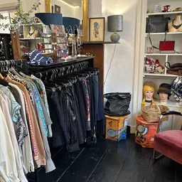 Rekken met tweedehands kleding, vintage accessoires en pop-up displays in de winkel