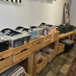 Houten kratjes met vinyl records, cd's en politie-petten op een houten tafel in de winkel
