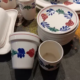 Serviesgoed met blauw-rode bloemenpatroon: gestapelde borden, een pot en een kom