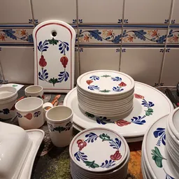 Servies met blauw-rood bloemdessin, gestapelde borden en enkele kopjes