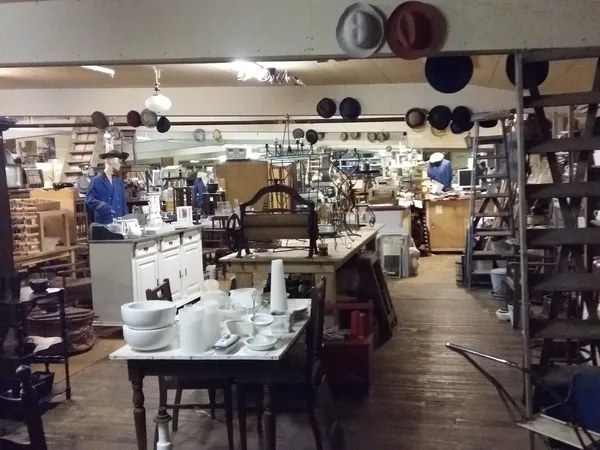Winkelvloer van kringloopwinkel met tafels, stellingen, servies en huishoudelijke artikelen