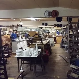 Winkelvloer van kringloopwinkel met tafels, stellingen, servies en huishoudelijke artikelen