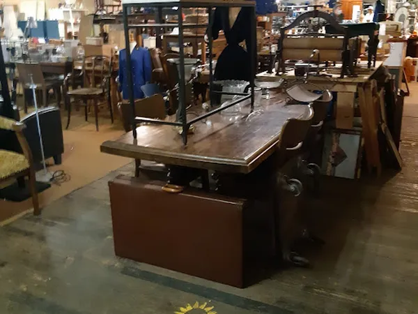 Werkruimte in kringloopwinkel met restauratietafel en werkbanken vol gereedschap en spullen