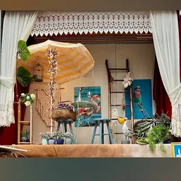 Etalage met vintage en tweedehands spullen: parasol, vogels, schilderijen, plantjes en decoratieve objecten