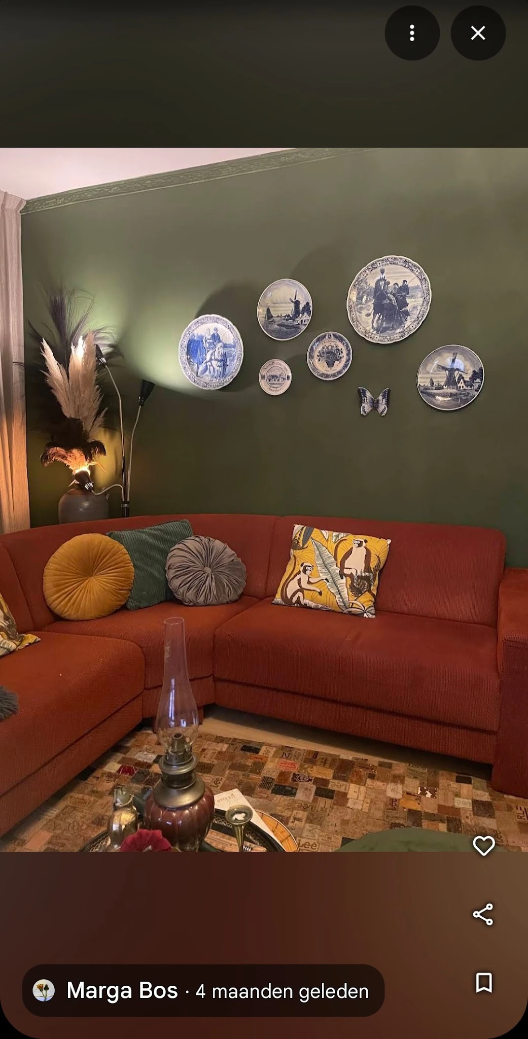Rood hoekbankje met kussens in de winkel, aan muur met groene verfkleur en decoratieve borden
