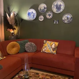 Rood hoekbankje met kussens in de winkel, aan muur met groene verfkleur en decoratieve borden
