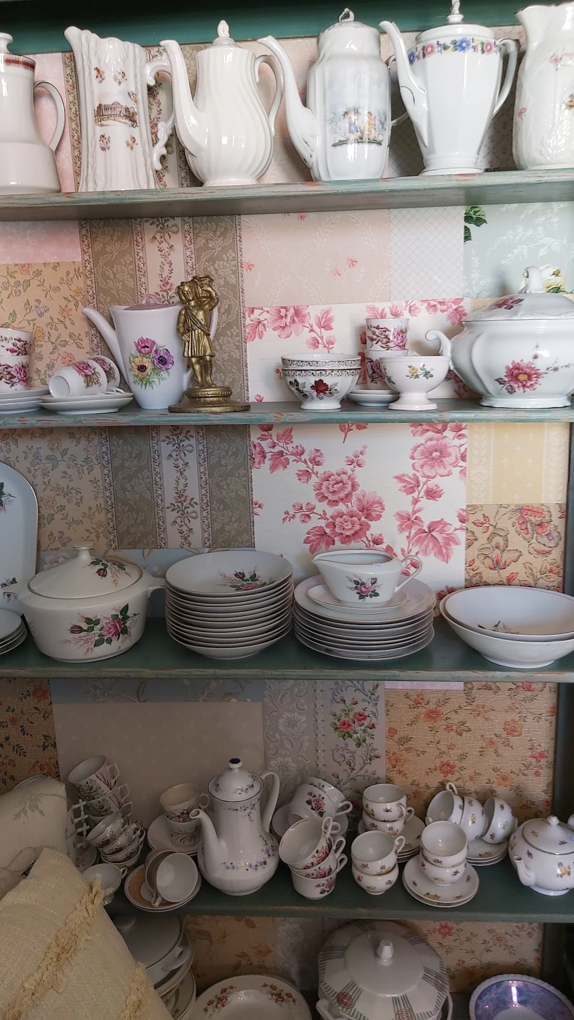 Stellingen met vintage porselein servies, kopjes en borden met bloemmotieven