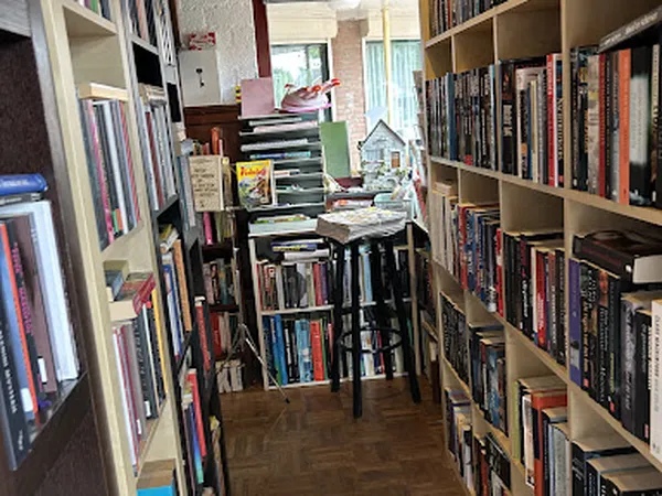 Gangetje tussen boeken- en dvd-stellingen met media op tafels in het midden
