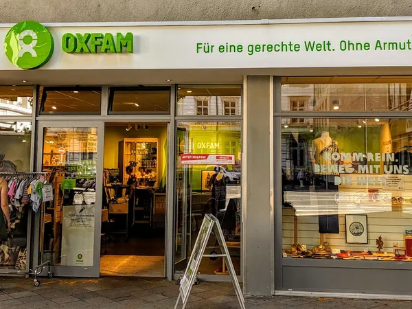 Gevel van Oxfam tweedehands winkel met groene letters, open deuren en uitstallingen in de etalage