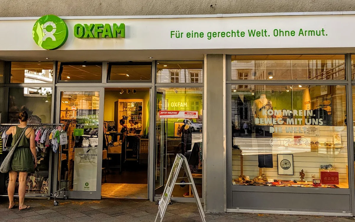 Gevel van Oxfam tweedehands winkel met groene letters, open deuren en uitstallingen in de etalage