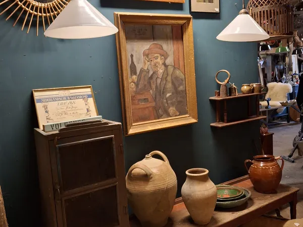 Winkelvloer met blauwe wand, kunstobjecten, klassieke lampen en antiek aardewerk uitgestald op houten meubels
