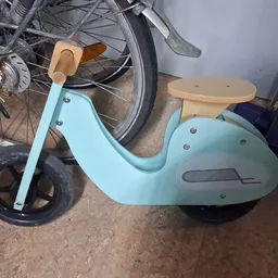 Turquoise loopfiets voor kinderen met houten zitting en zwarte wielen