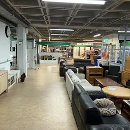 Ruim winkelinterieur met meubels, banken en diverse spullen uitgestald op de vloer en stellingen